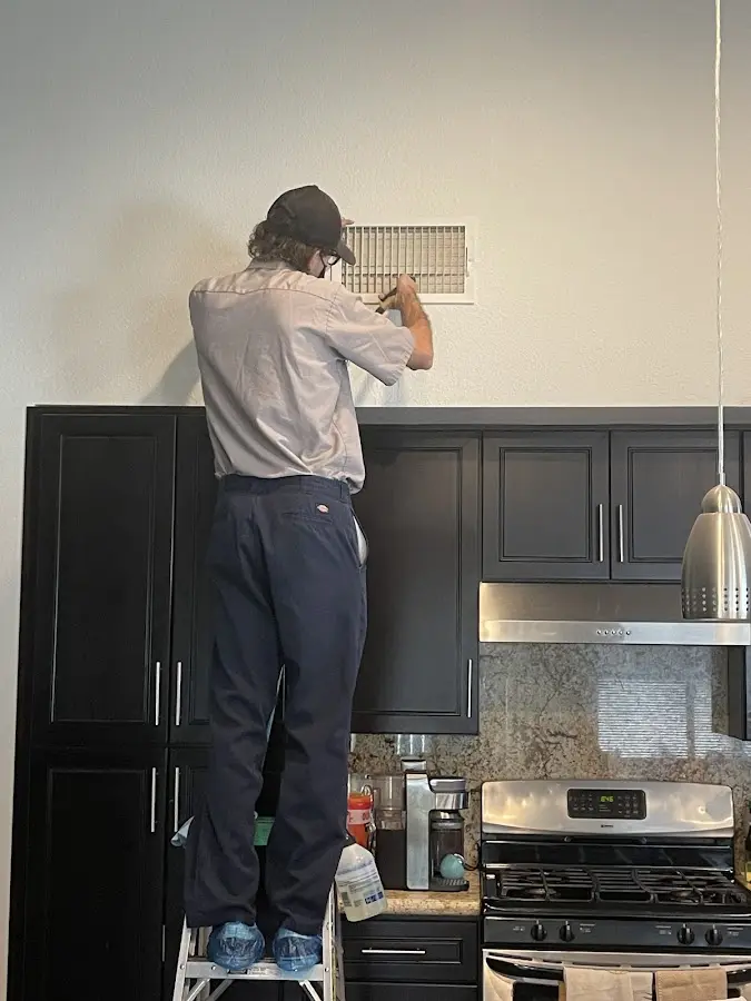 Technician inspecting an air vent during HVAC service in Whitfield
